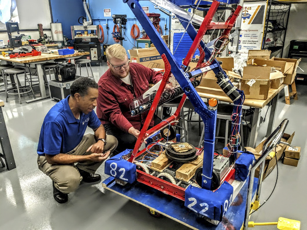 A robot by Cleveland public high schoolers gets looked over by JonDarr Bradshaw of the Great Lakes Science Center, left, and Tim Hatfield of Argonaut
