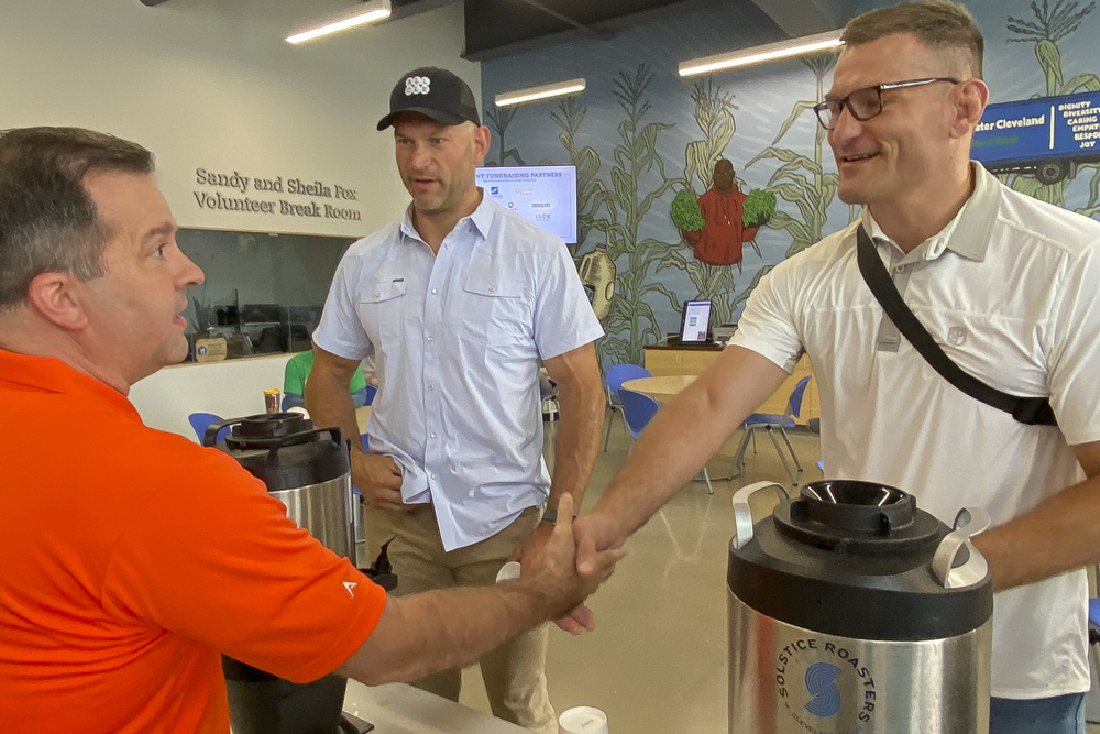 Joe Thomas  and Stipe Miocic serve All Cleveland Coffee to staff members at the Greater Cleveland Food Bank