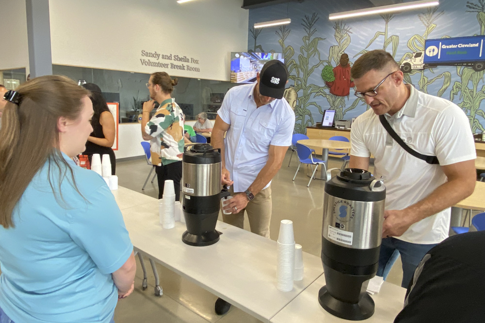 Joe Thomas  and Stipe Miocic serve All Cleveland Coffee to staff members at the Greater Cleveland Food Bank