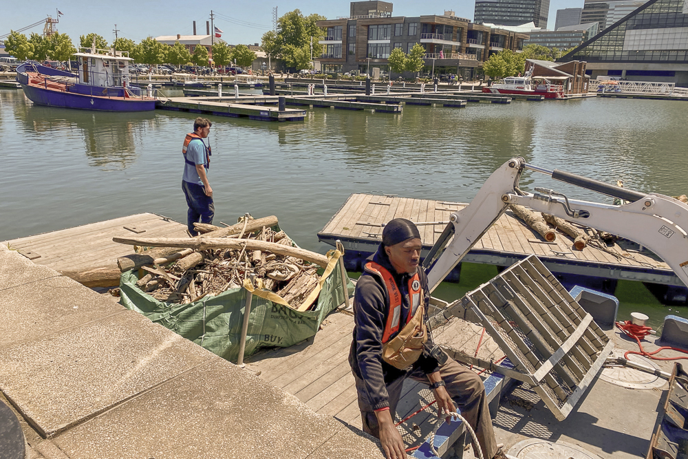 Crew members going around North Coast Harbor docs with skimmers to get smaller debris