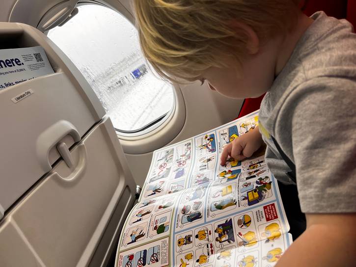 Balliett's son on an airplane, looking at the emergency evacuation procedures. When she pitched, she used the trifold as an example of how comics are used every day to bridge language and reading barriers.