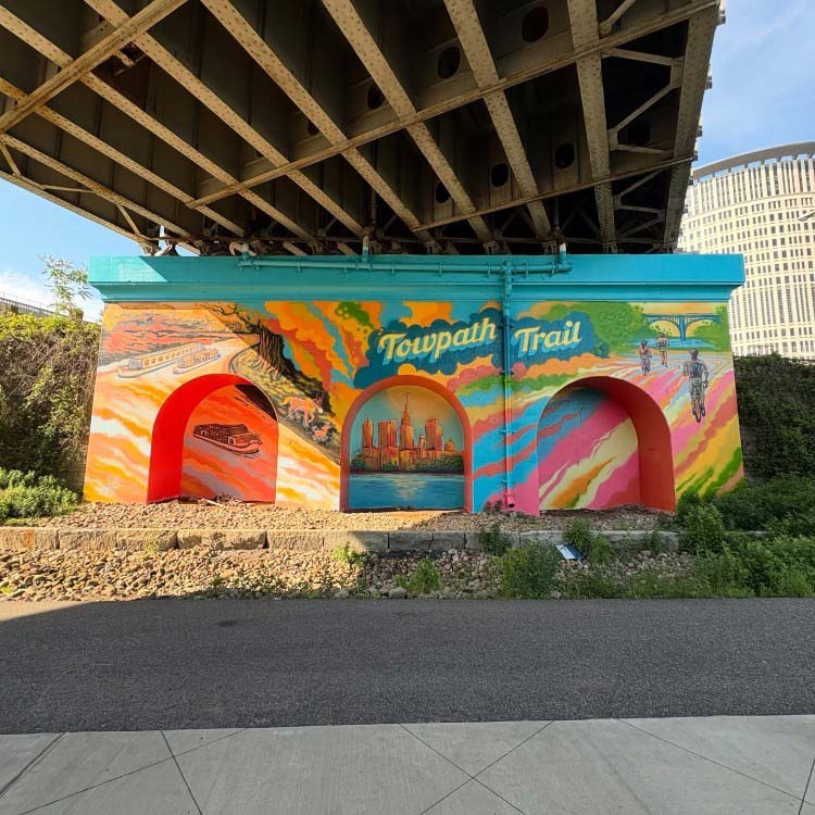 “Canal Basin Park’s Towpath Trail Mural” progresses from sepia tones in historic days to vibrant colors. to depict the future.