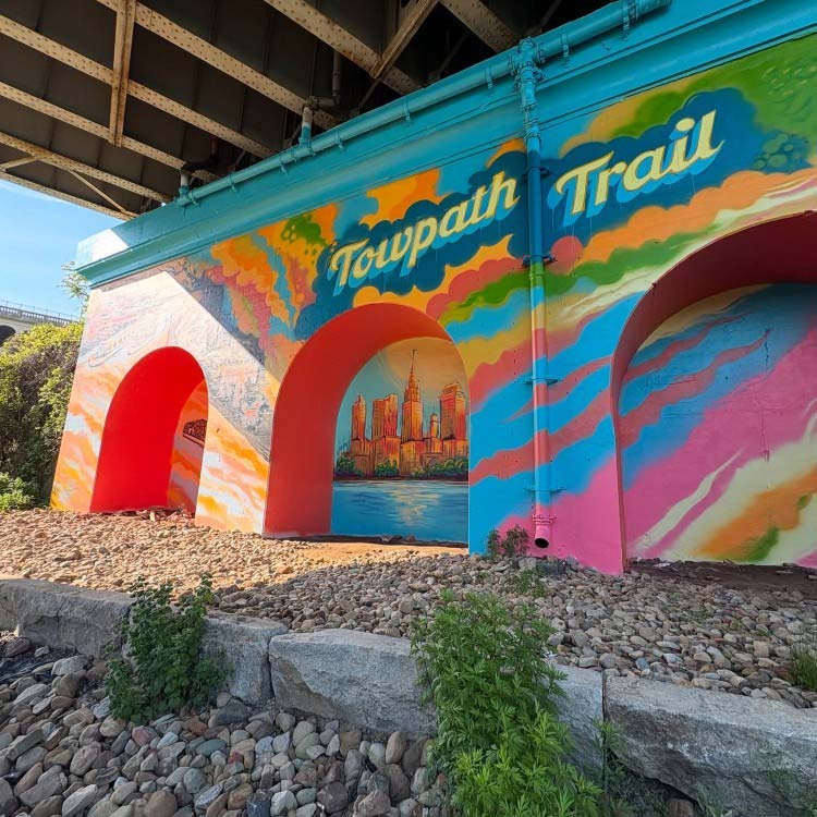 “Canal Basin Park’s Towpath Trail Mural”  progresses from sepia tones to vibrant colors.