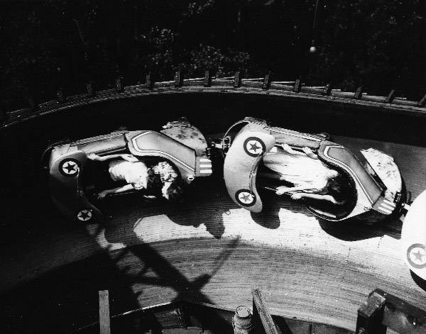 Cars on Euclid Beach's  Flying Turns ride, zooming around a corner loaded with riders.