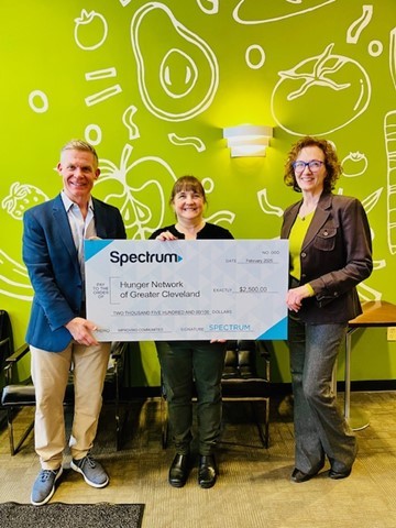 Julie Johnson, middle, with the Hunger Network, receives a check from Spectrum's Mike Chase and Renee Copfer,.
