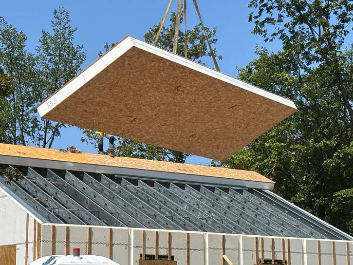 A crane lowers the roof on the energy positive duplexes.