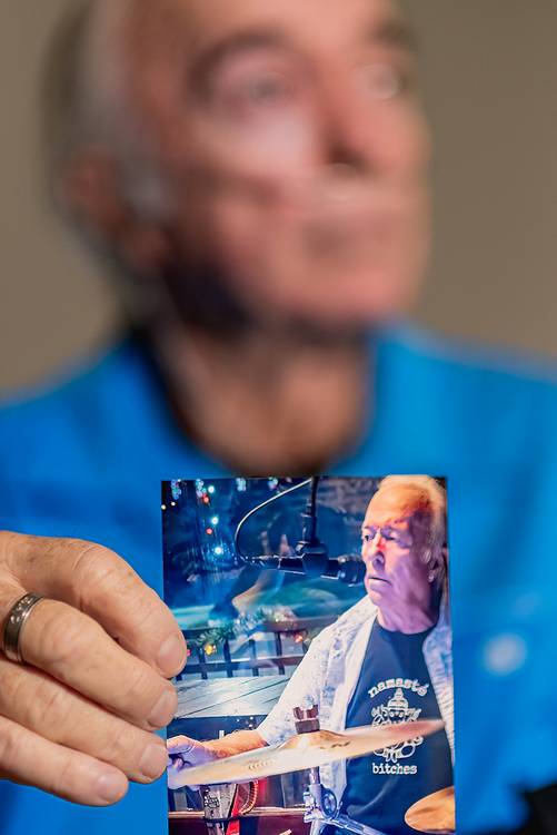 Tim holds up a photo of himself drumming.