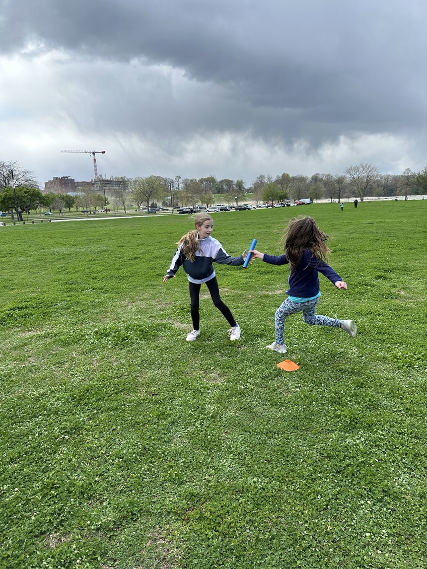 Run Your City Cleveland participants in a relay hand-off.