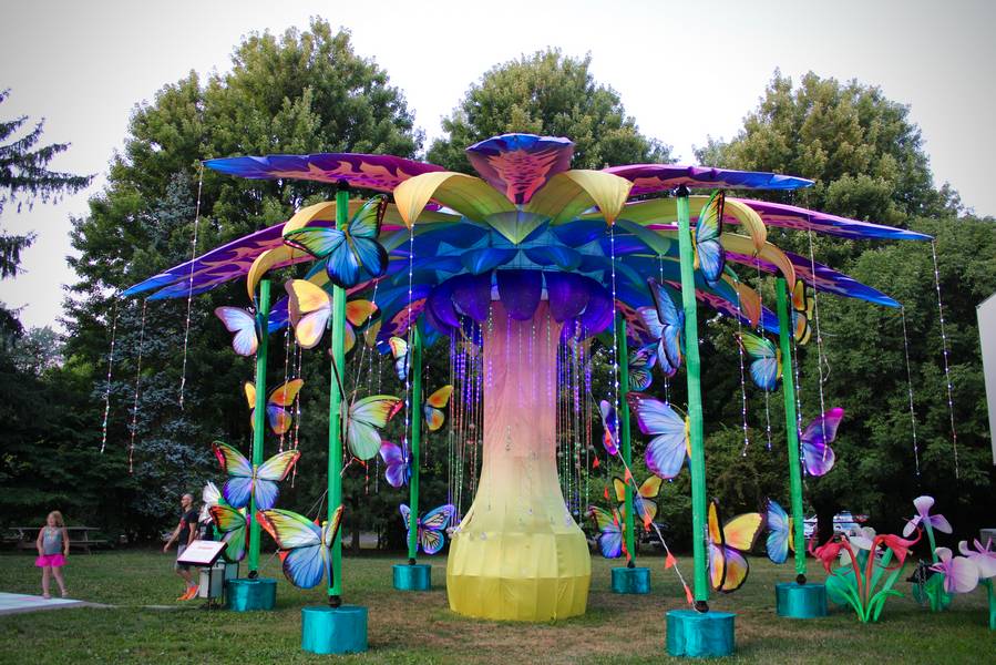 A huge butterfly tree stands next to a stage with live entertainment.