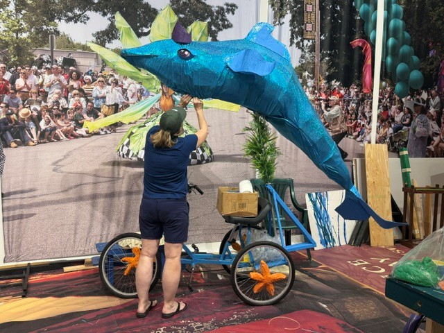 A volunteer builds a dolphin ridding a bicycle for Parade the Circle.