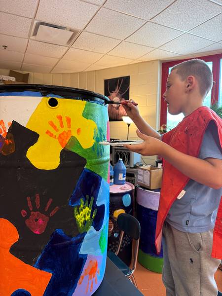 A student puts the final painting touches on a rain barrel.