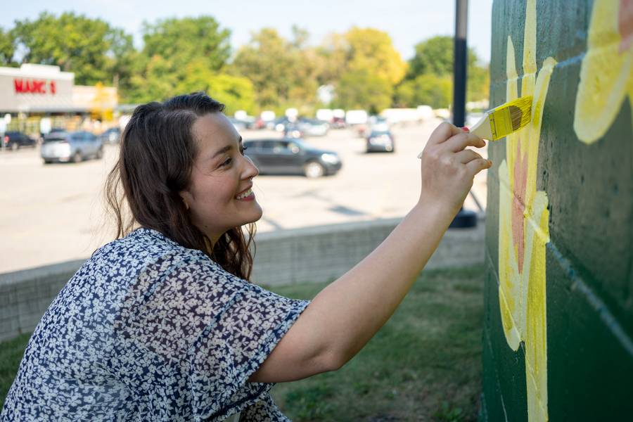 Artist Olivia Oltmanns works on her mural, 'Grow Together' on Messenger Court in South Euclid,