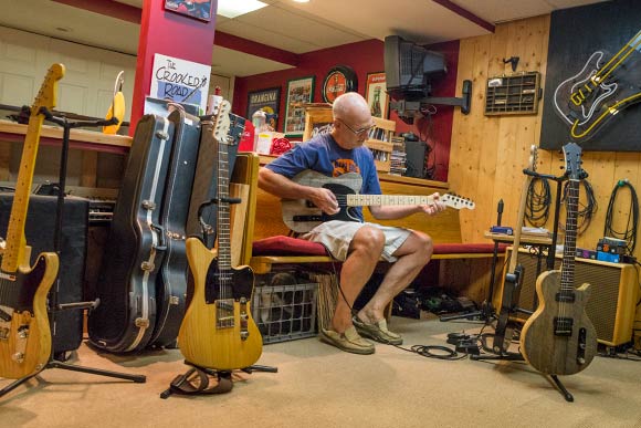 David Lackey playing one of his guitars at his home