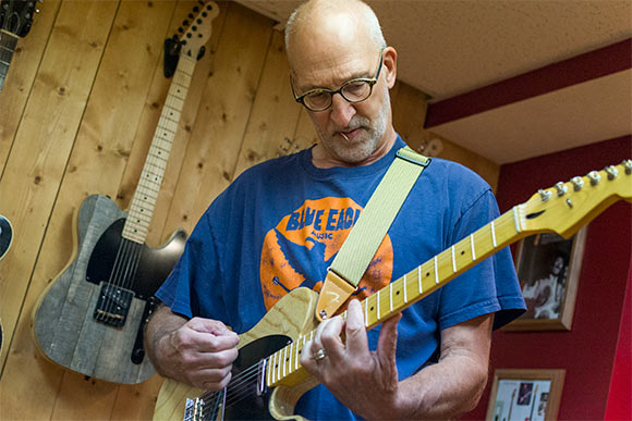 <span class="content-image-text">David Lackey playing one of his guitars at his home</span>