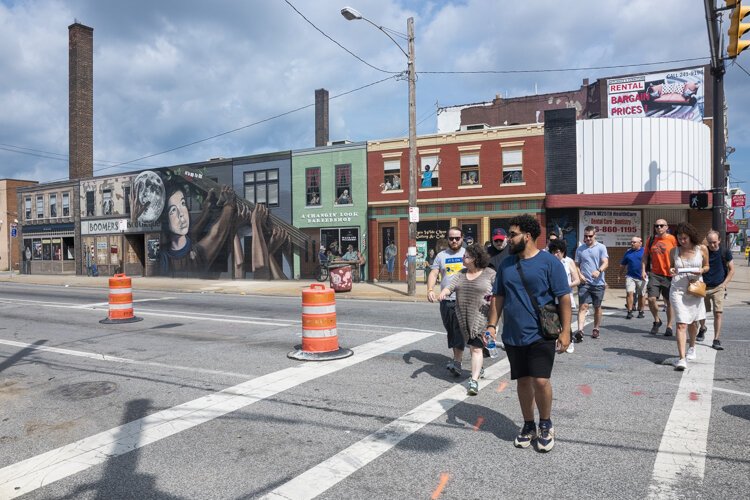 Metro West Community Development Organization's Ricardo Leon leads the walking tour past the It's Up to Us mural on Clark Avenue and West 25th Street.