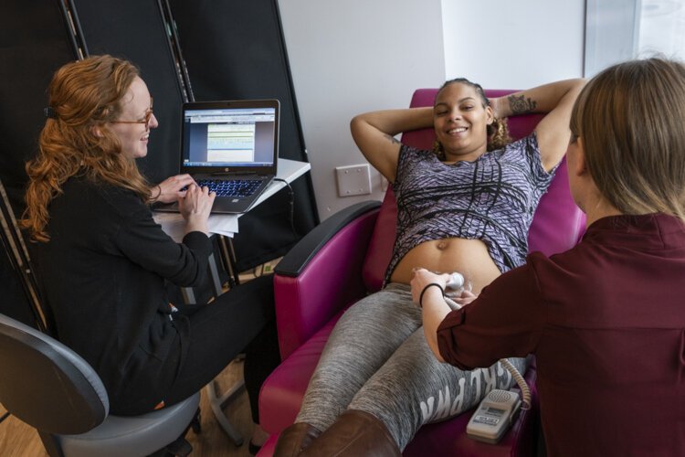 An expecting mom gets a sonogram from Amy, the midwife for the group, with help from her medical student.