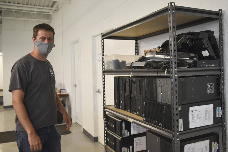 Bryan Mauk, executive director for the nonprofit PCs for People, stands near a shelf that holds computers that people can get for low- or no cost.