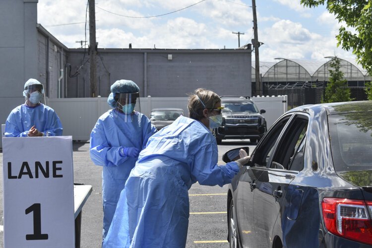 Dr. Heidi Gullett, center, Cuyahoga County Board of Health’s medical director, explains the process to a driver who came through a pop-up COVID-19 testing site located at the Word Church on Kinsman Road in Cleveland back in early June.