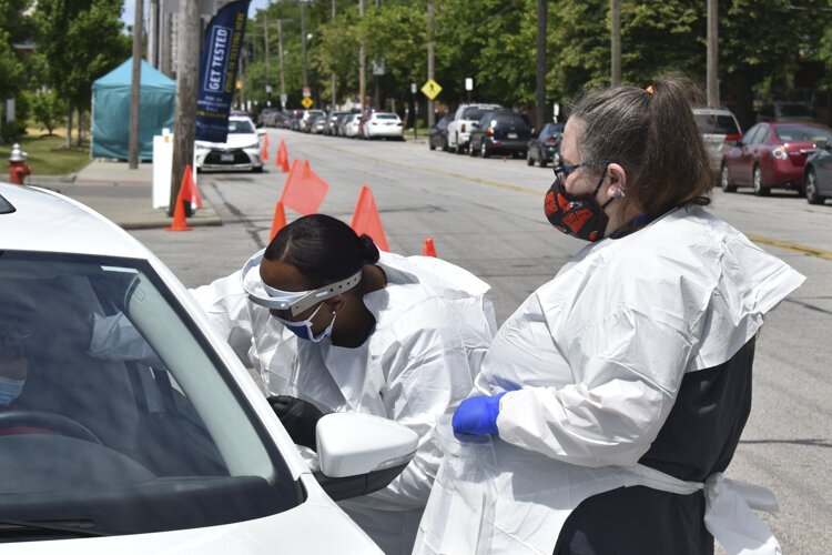 Andrea Mathews, left, a registered nurse with Care Alliance Health Center, gives a driver a COVID-19 test at the Care Alliance Health Center’s Central Neighborhood Clinic on Central Avenue in Cleveland.
