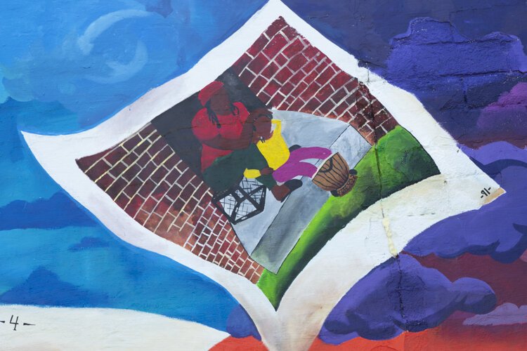 Storytime (BLM)” depicts a young Black boy under a tree, reading a story about his ethnicity and his family. The artists are Lacy “Lacerrrr” Talley, Michelle Suells, Aldonte Flonnoy, and Niquo Braxton.